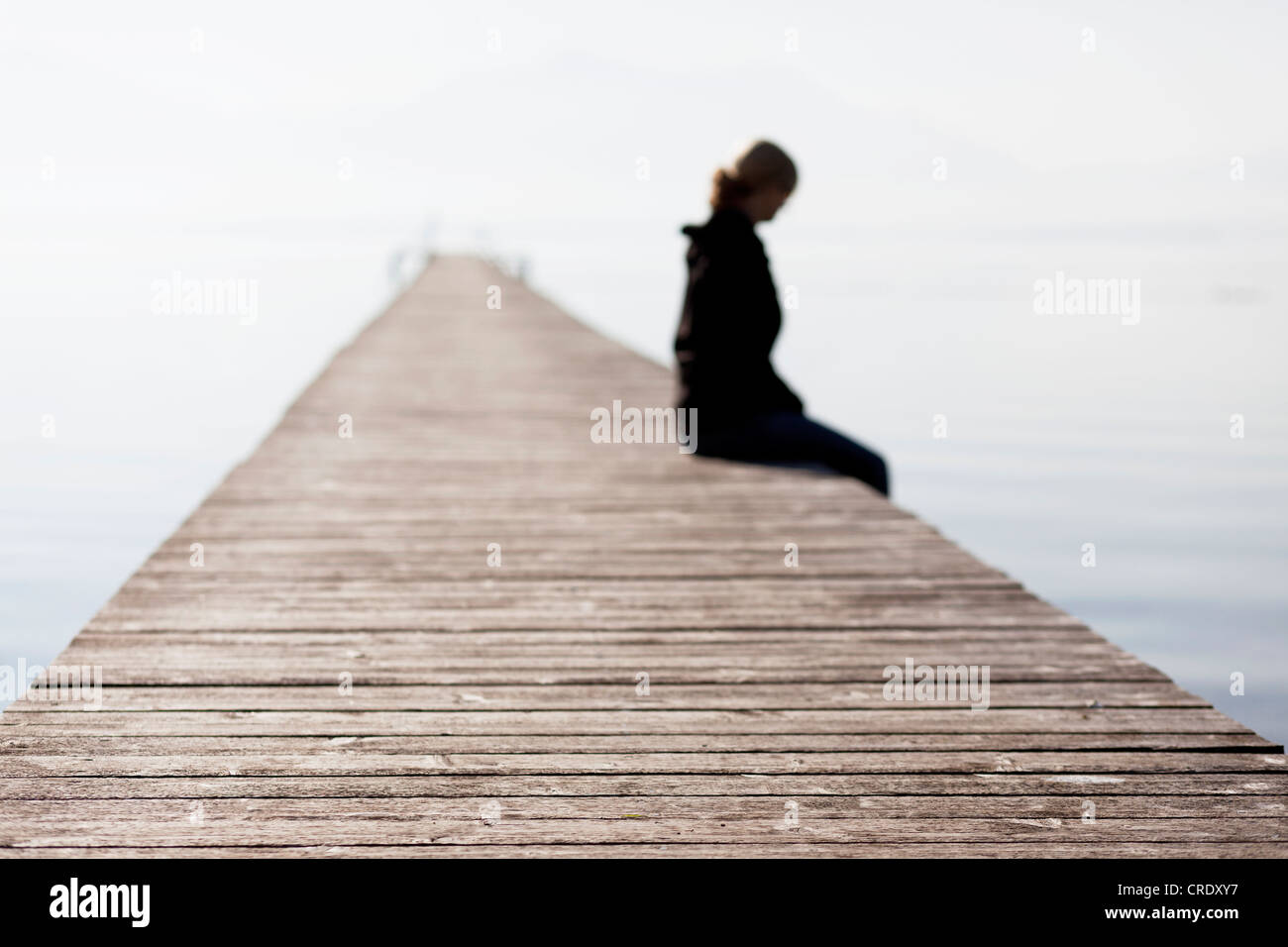La donna seduta su un molo in legno, calzature, il Lago Chiemsee, Baviera, Germania, Europa PublicGround Foto Stock