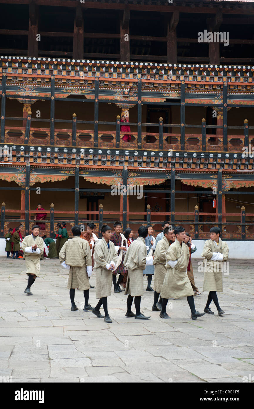 Il Tibetano buddista festival, uomini che indossano il tradizionale abito Gho, Rinpung Dzong Monastero e fortezza, cortile, Paro Foto Stock