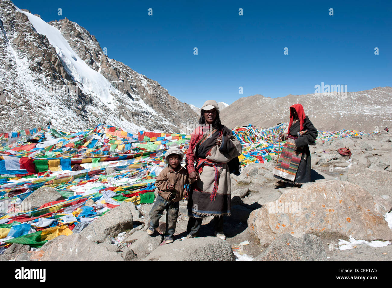 Buddismo tibetano, molti colorati bandiere di preghiera, la famiglia con il piccolo bambino all'Dolma La Pass, 5670m, pellegrinaggio strada intorno al santo Foto Stock