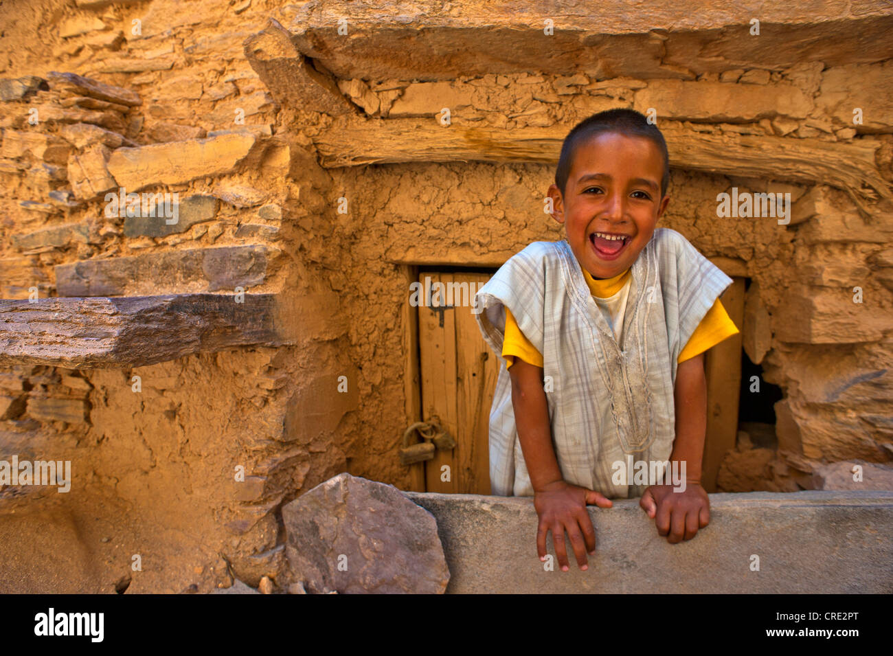 Felice ragazzo davanti all'ingresso di una camera, Tasguent castello di storage, Anti-Atlas, sud del Marocco, Marocco, Africa Foto Stock