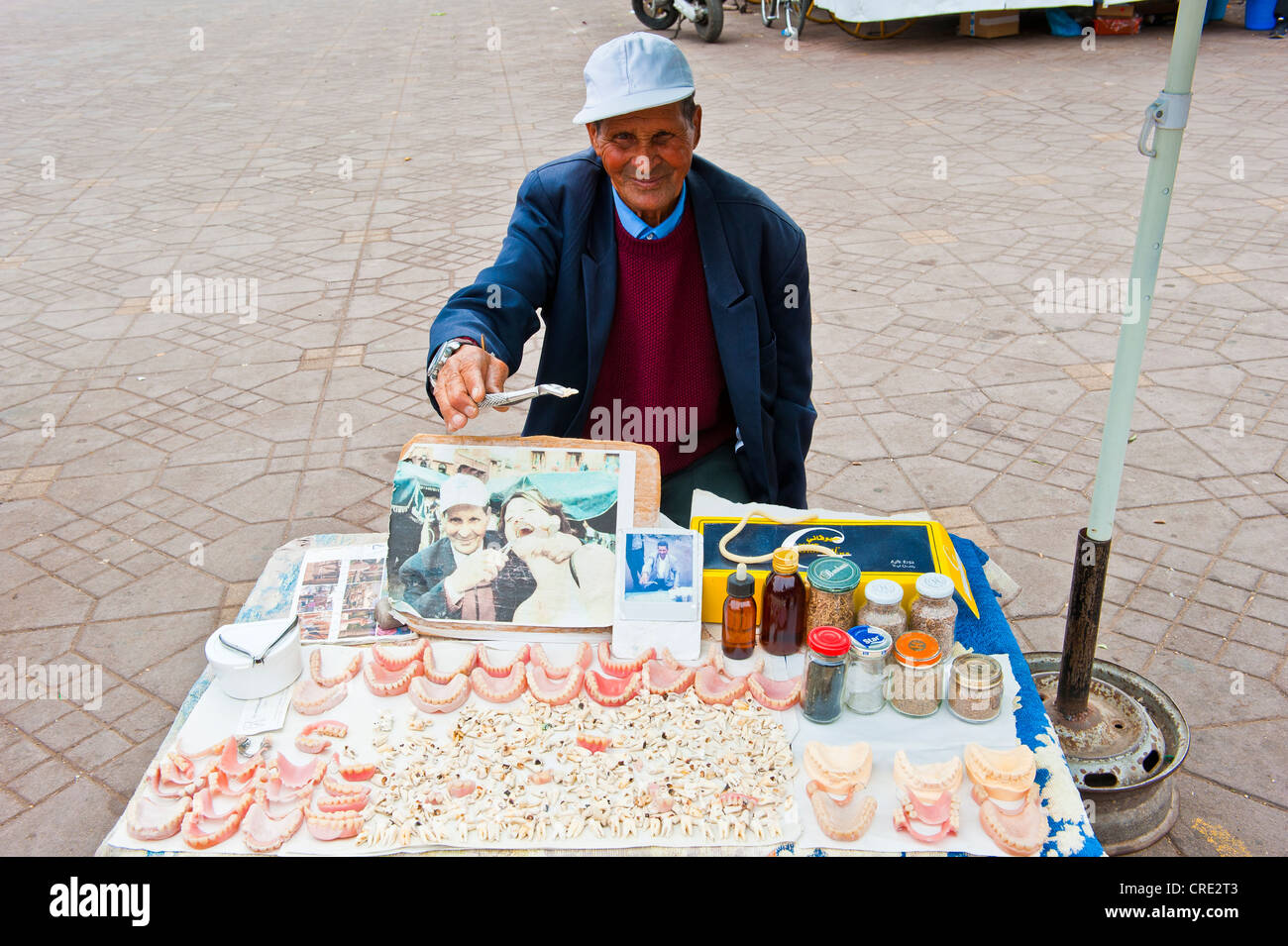 Un uomo anziano, dente medico, offrendo i denti e protesi in vendita presso il suo stand, Djemaa el Fna, quadrato dell'impiccato, Marrakech Foto Stock