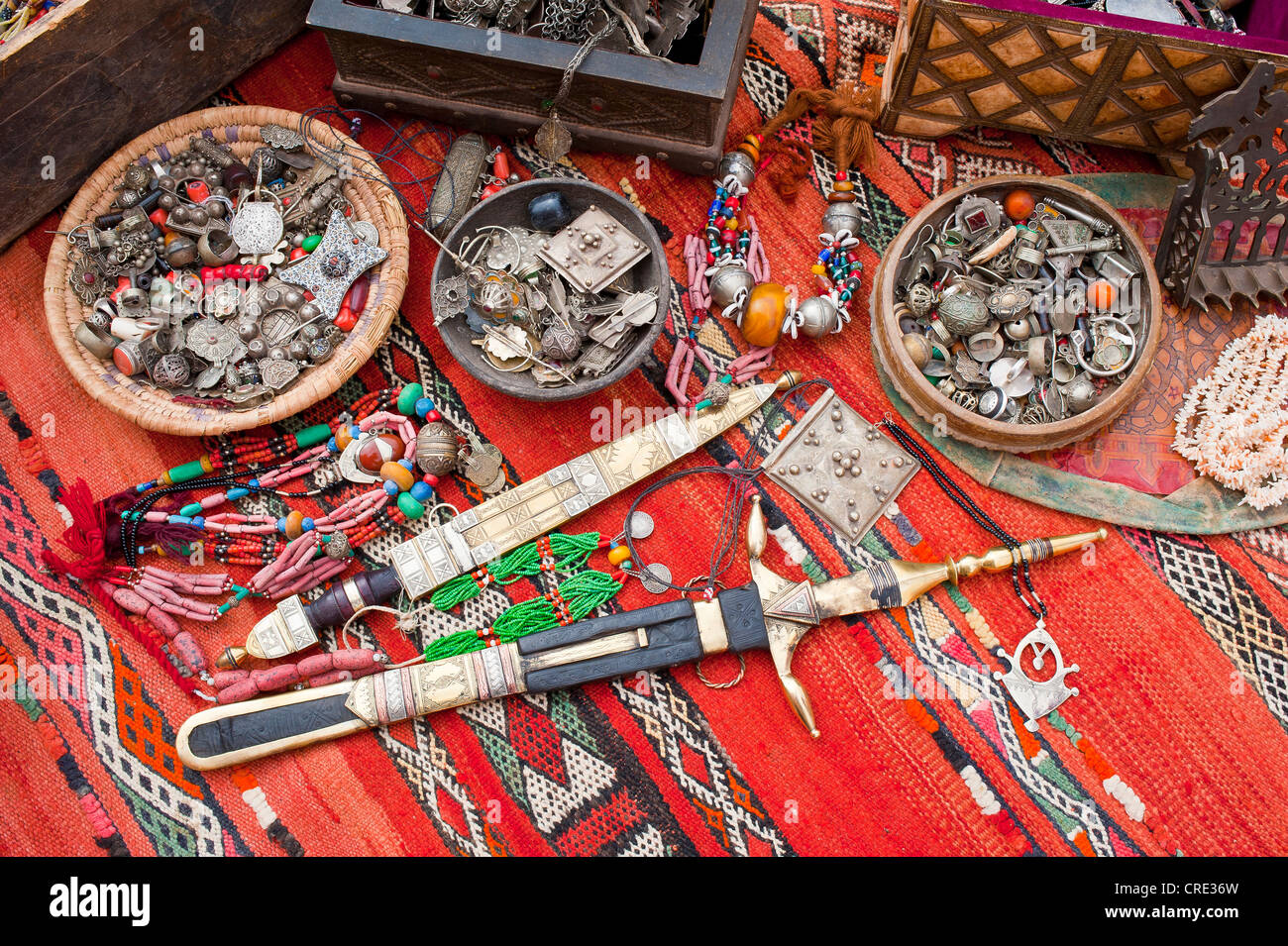 Gioielli orientali, piccoli scrigni di un tesoro e ornato Touareg coltelli sono sparsi su un tappeto in un souk o bazaar, Marocco, Africa Foto Stock