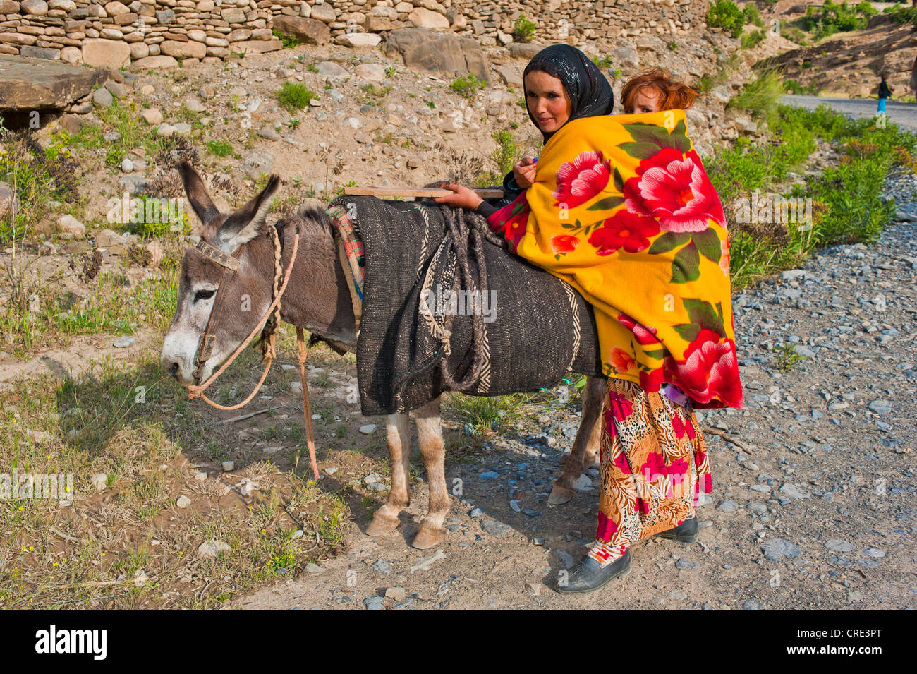 Giovane madre in viaggio con un asino e portando il suo bambino in una imbracatura sulla sua schiena, Alto Atlante, Marocco, Africa Foto Stock