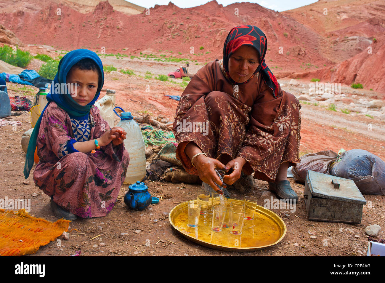 Grotta di nomadi di abitazione, una donna e un po' di ragazza seduta davanti a una grotta abitazione, la donna è il tè di pulizia occhiali su un Foto Stock