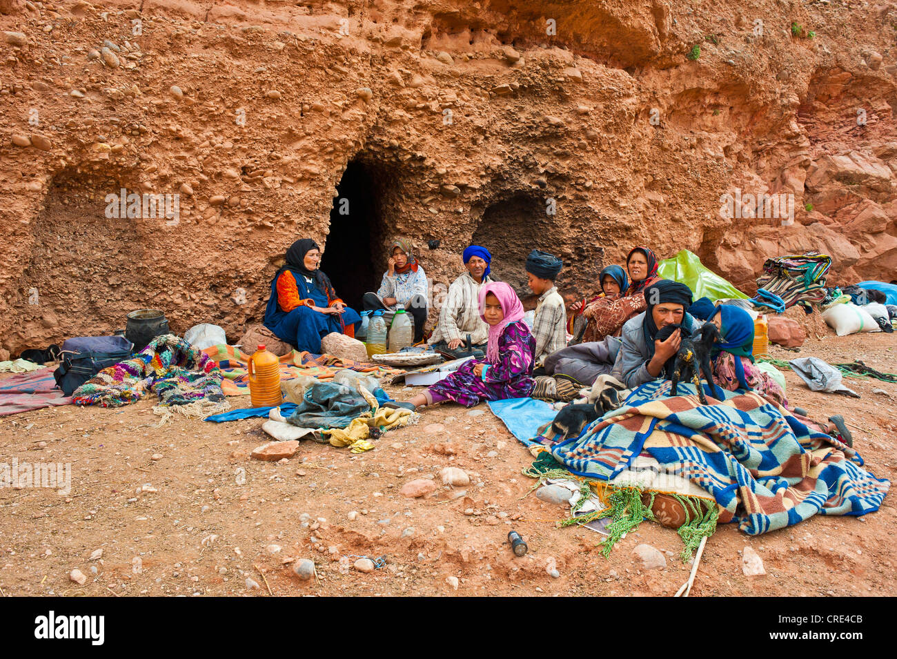 Grotta di nomadi-abitanti, dei berberi, una famiglia con molti bambini seduti davanti alla loro grotta-abitazione, Dades Valley Foto Stock