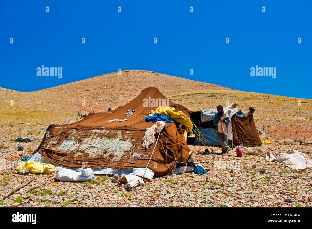 Uomo in piedi nella parte anteriore della sua tenda nomade che è stato patchato varie volte, sud del Marocco, Marocco, Africa Foto Stock