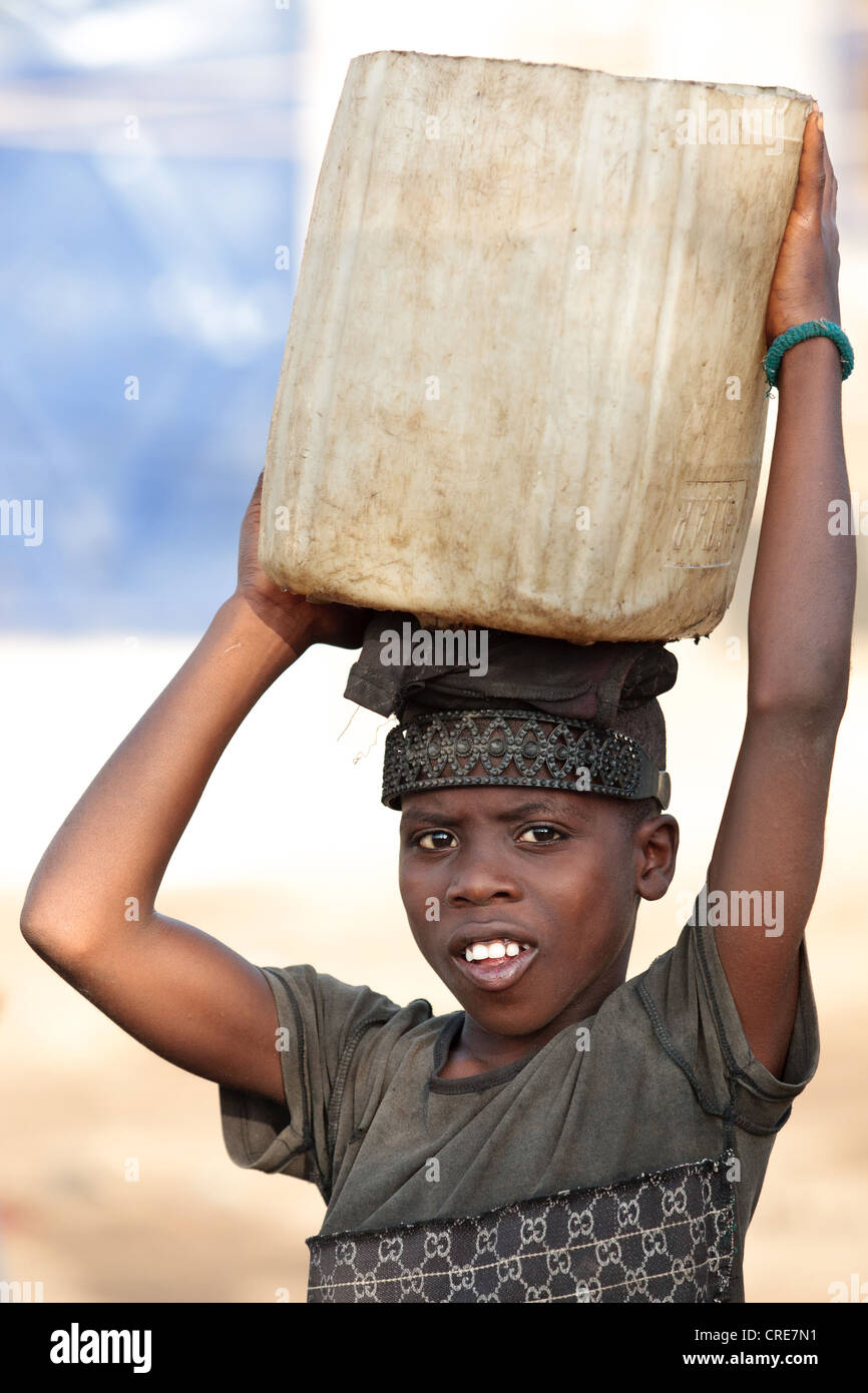 Un ragazzo porta un taniche di acqua sulla sua testa nel Clara città baraccopoli di Monrovia, Montserrado county, Liberia Foto Stock
