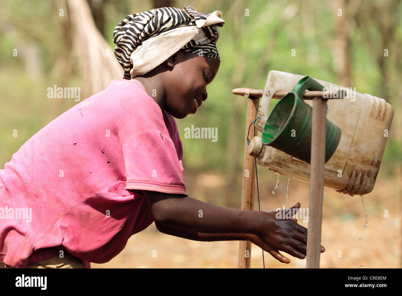 Una ragazza lava le mani in un pedale azionato a mano la stazione di lavaggio al di fuori di una latrina home Foto Stock