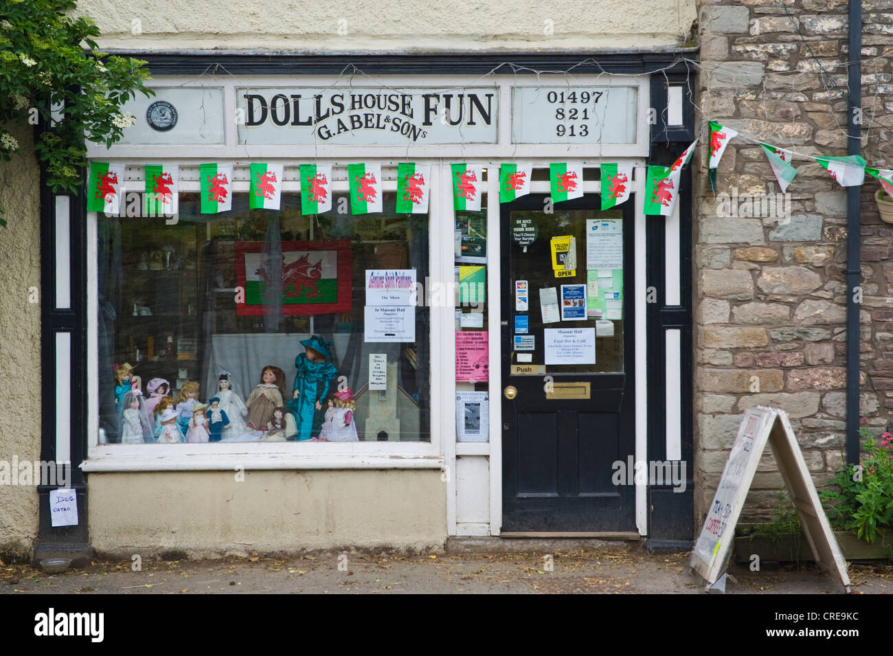 Welsh drago rosso bandiera bunting su Dolls house shop on high street a Hay-on-Wye Powys Wales UK Foto Stock