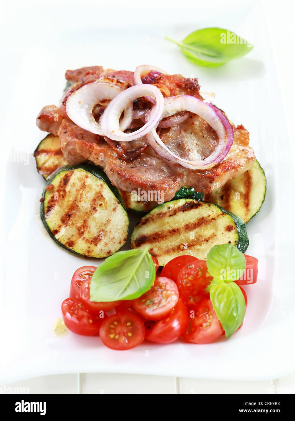 In padella bistecca di carne di maiale con verdure grigliate e insalata di pomodoro Foto Stock