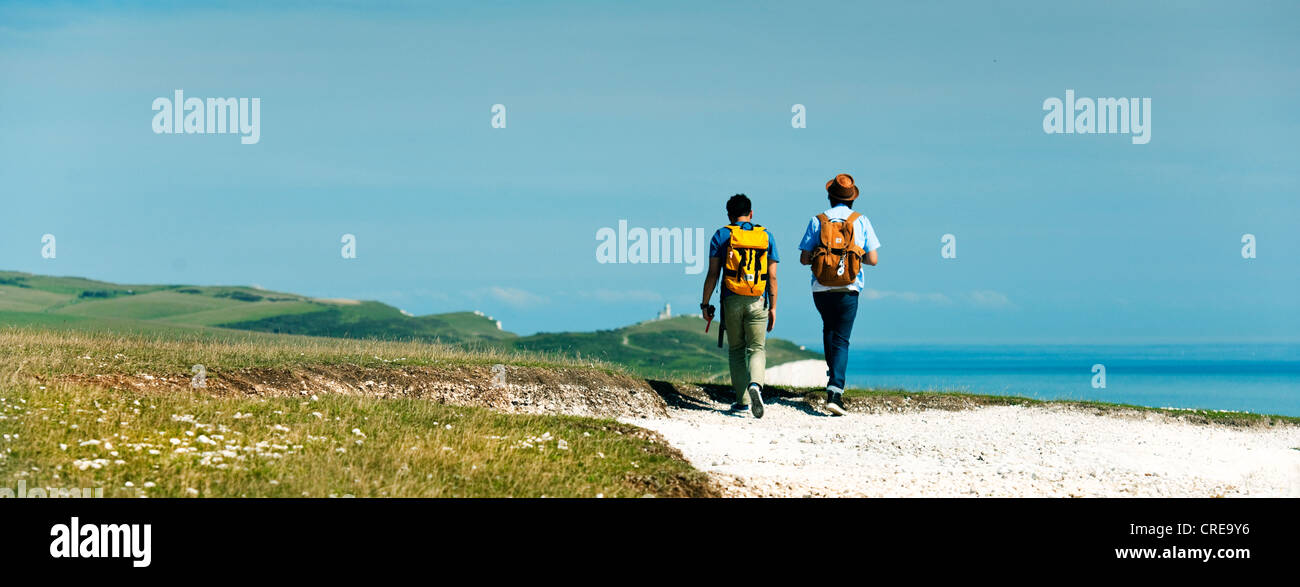 Due persone che camminano su sette sorelle sul South Downs verso Belle Tout faro. Una giornata di sole con il blu del cielo e del mare Foto Stock