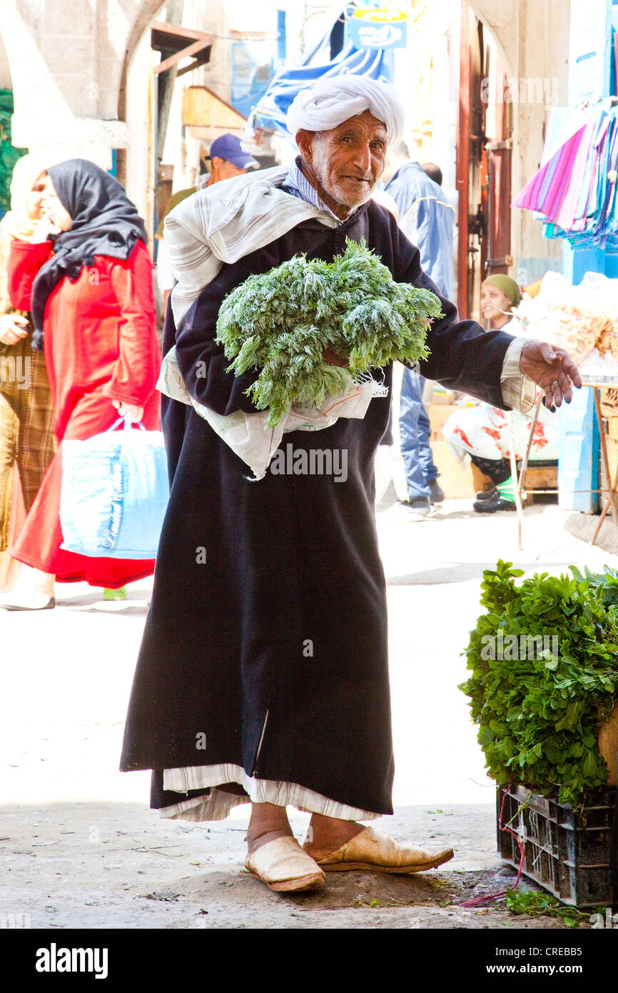 Uomo che indossa un djellaba tradizionale per il suo shopping al mercato o souk nel centro storico o medina Foto Stock