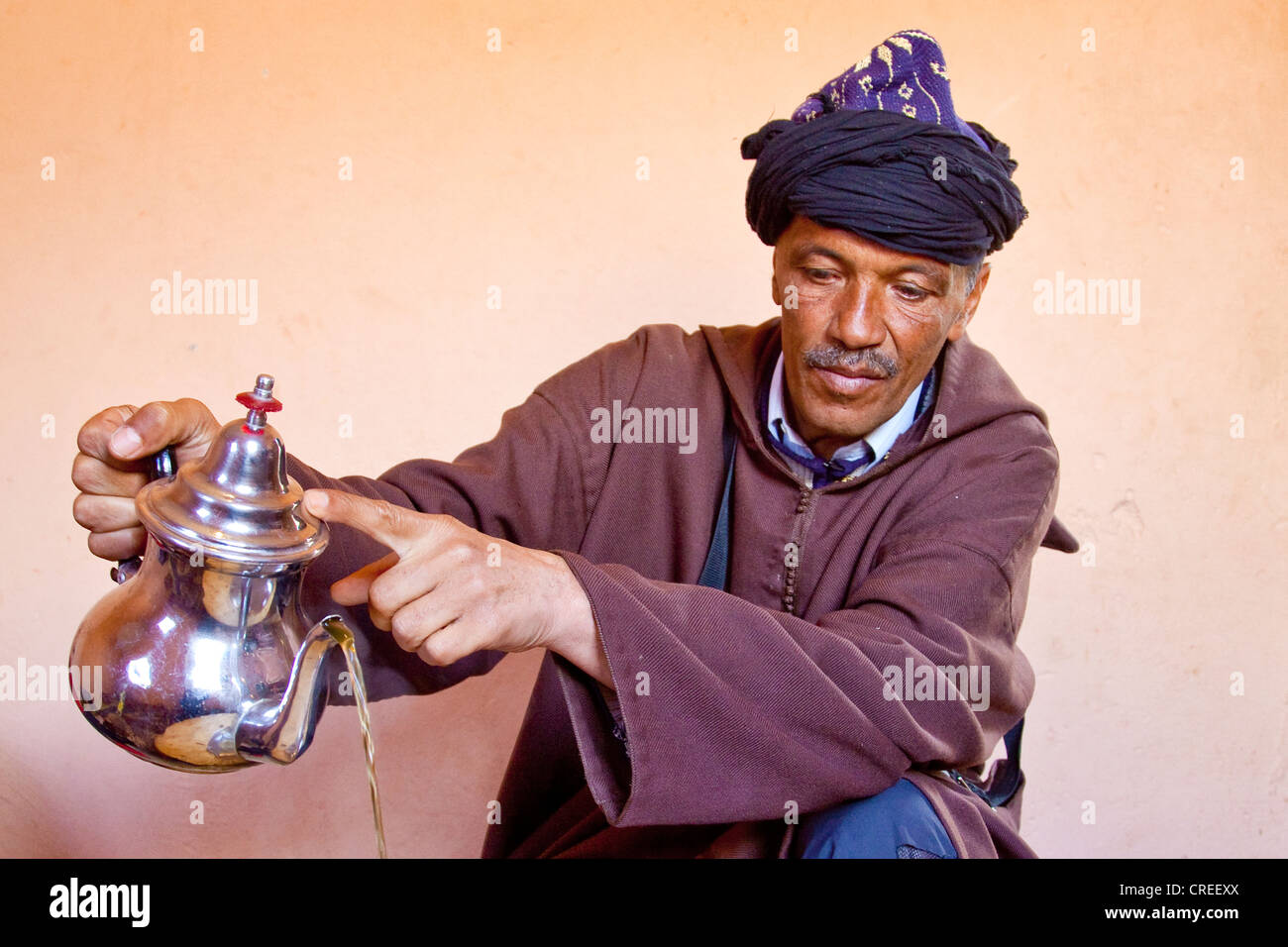 Berber indossando un Djellaba, un abito tradizionale, versando il tè alla menta, Alto Atlante vicino Asni, Marocco, Africa Foto Stock