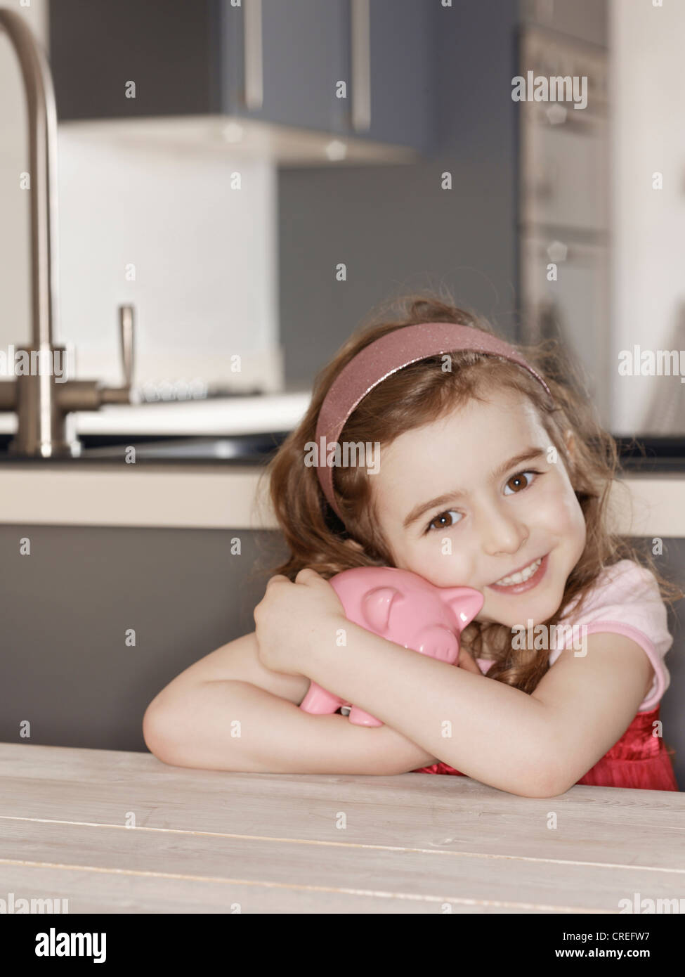 Ragazza sorridente abbracciando salvadanaio Foto Stock