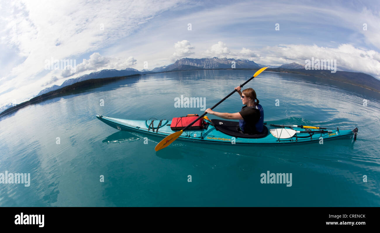 Giovane donna in un mare kayak o canoa, kayak di mare, montagne dietro, Tagish Highland, Atlin Lake, British Columbia, Canada Foto Stock