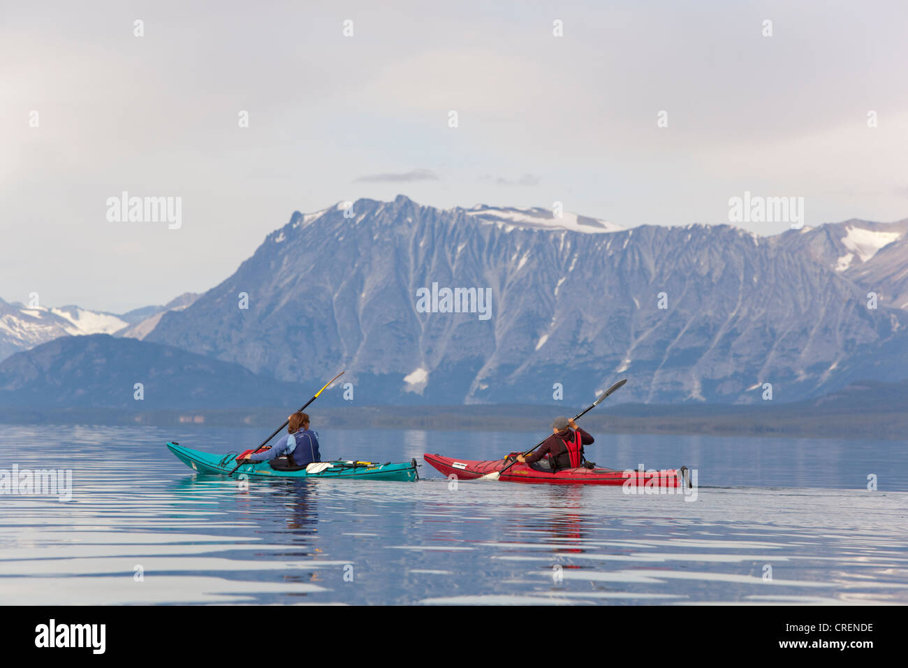 Due donne in kayak da mare o canoa, kayak di mare, montagne dietro, Tagish Highland, Mount Fetterly, Atlin Lake, British Columbia Foto Stock
