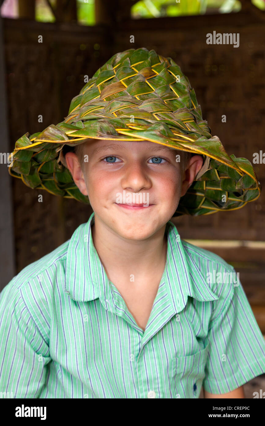 Ragazzo che indossa un cappello realizzato in tessuto di foglie, nei pressi di Ubud, centro di Bali, Bali, Indonesia, sud-est asiatico Foto Stock