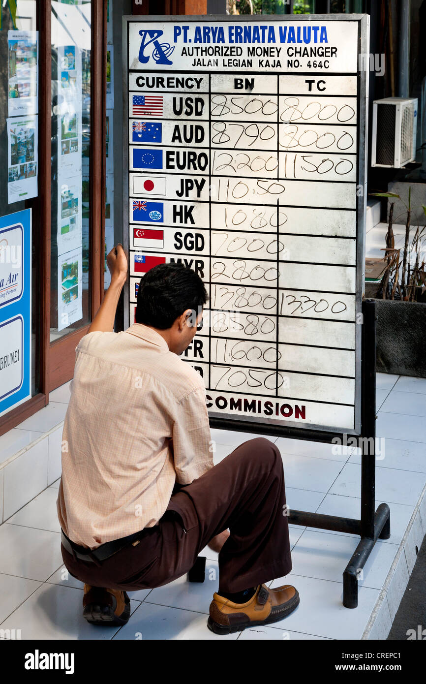 Uomo che legge i tassi di cambio su un bordo, Kuta, meridionale di Bali, Bali, Indonesia, Asia sud-orientale, Asia Foto Stock