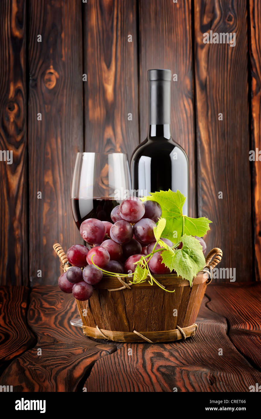 Vino rosso con un bicchiere di vino su sfondo di legno Foto Stock