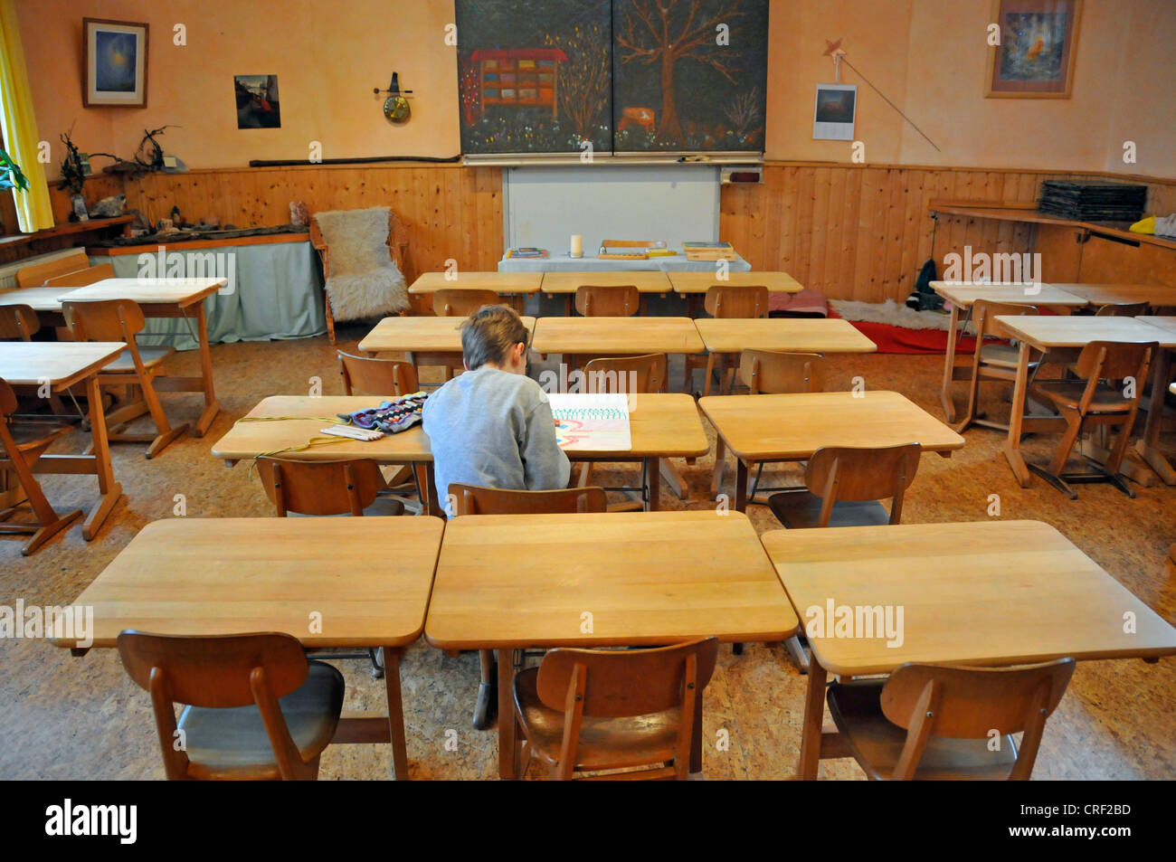 Otto anni scolaro seduto solitario in aula Foto Stock