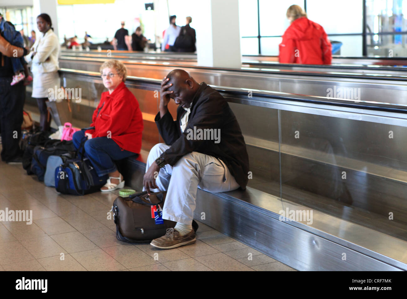 Stanco viaggiatore maschio in attesa del volo di collegamento all'aeroporto di Francoforte Foto Stock