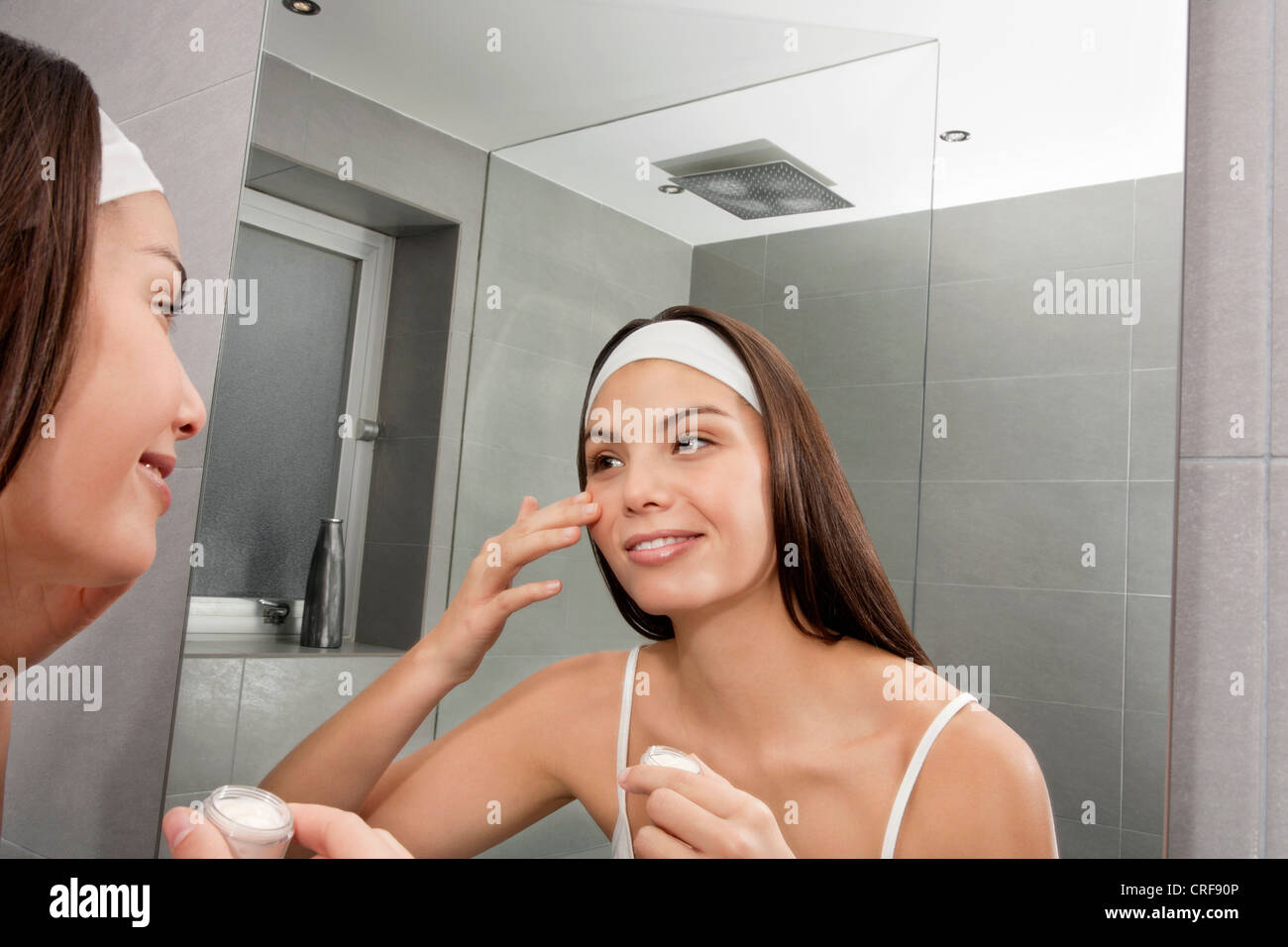 Donna esaminando il suo volto in specchio Foto Stock