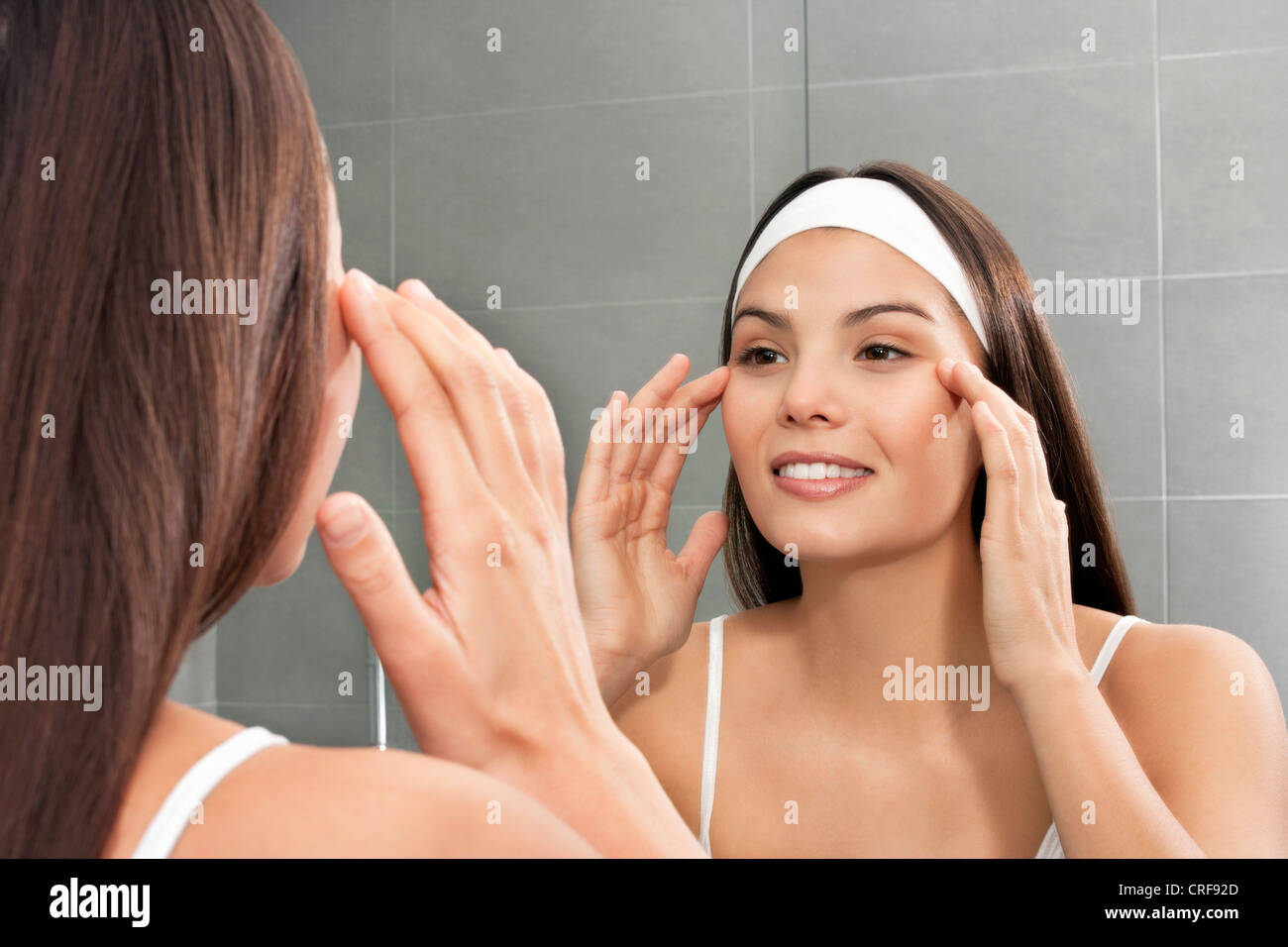 Donna esaminando il suo volto in specchio Foto Stock