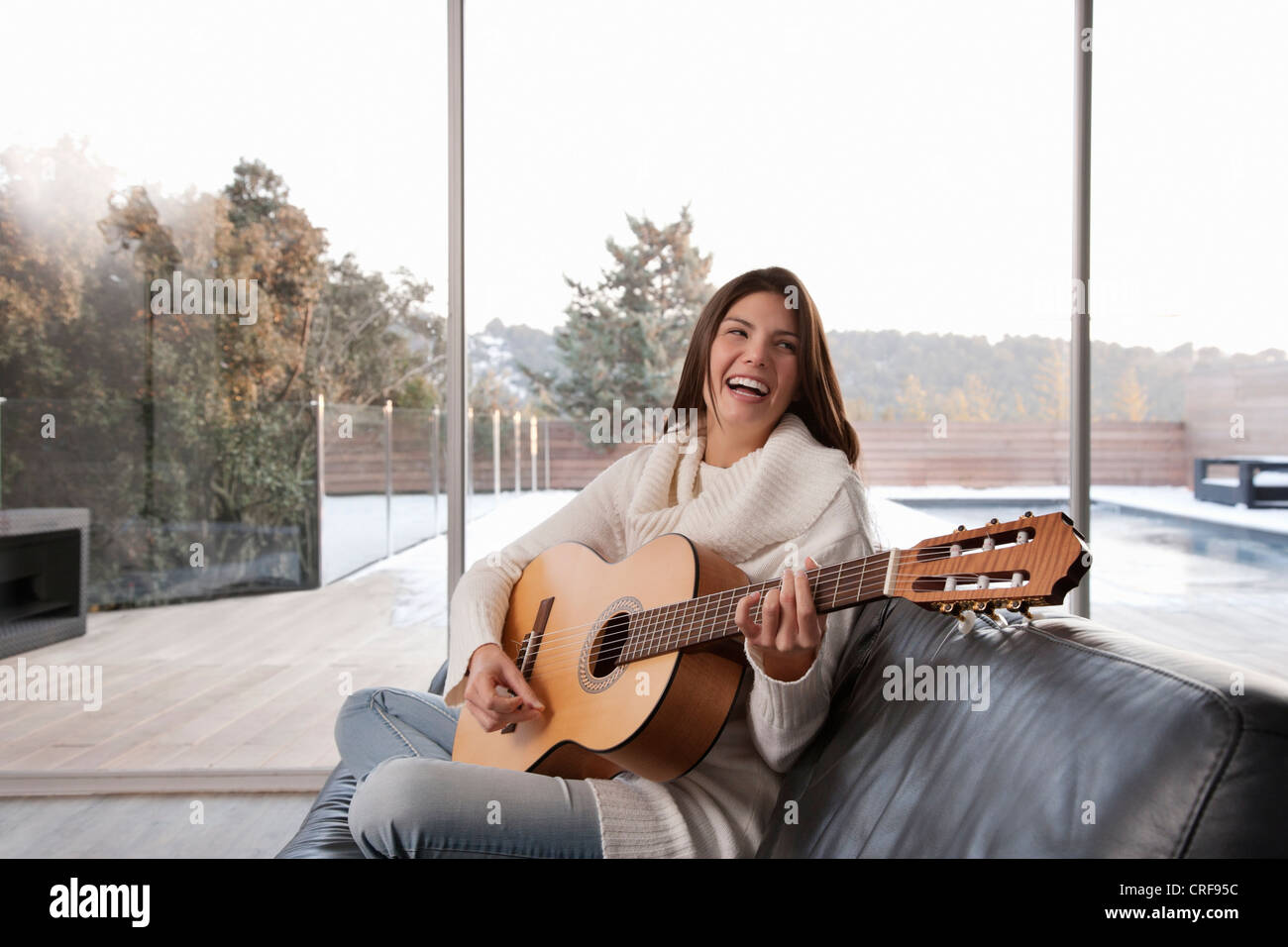 La donna a suonare la chitarra in salotto Foto Stock