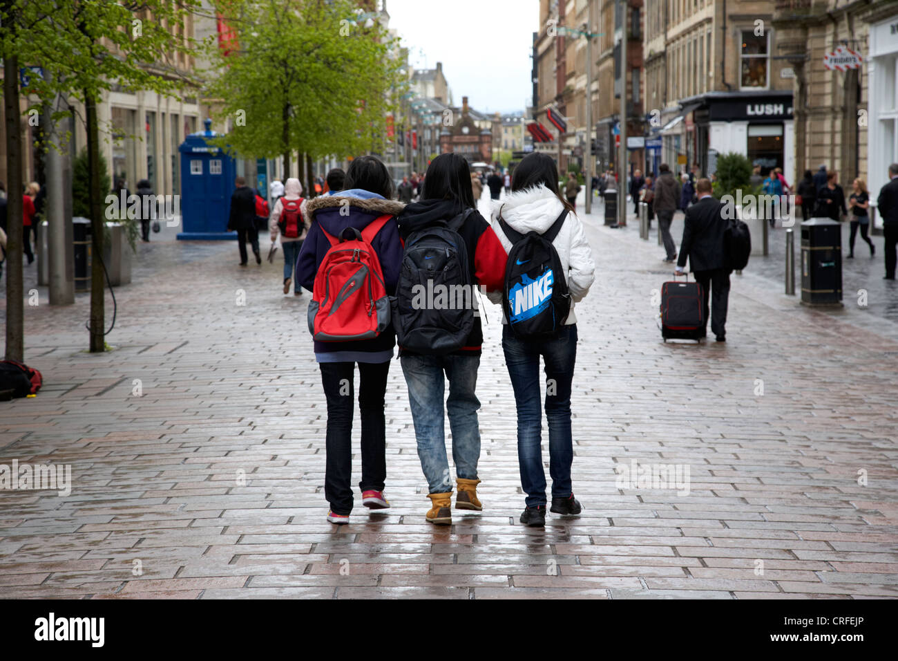 Tre femminili turisti asiatici a piedi lungo la pioggia inzuppato di Buchanan Street area shopping di Glasgow Scotland Regno Unito Foto Stock