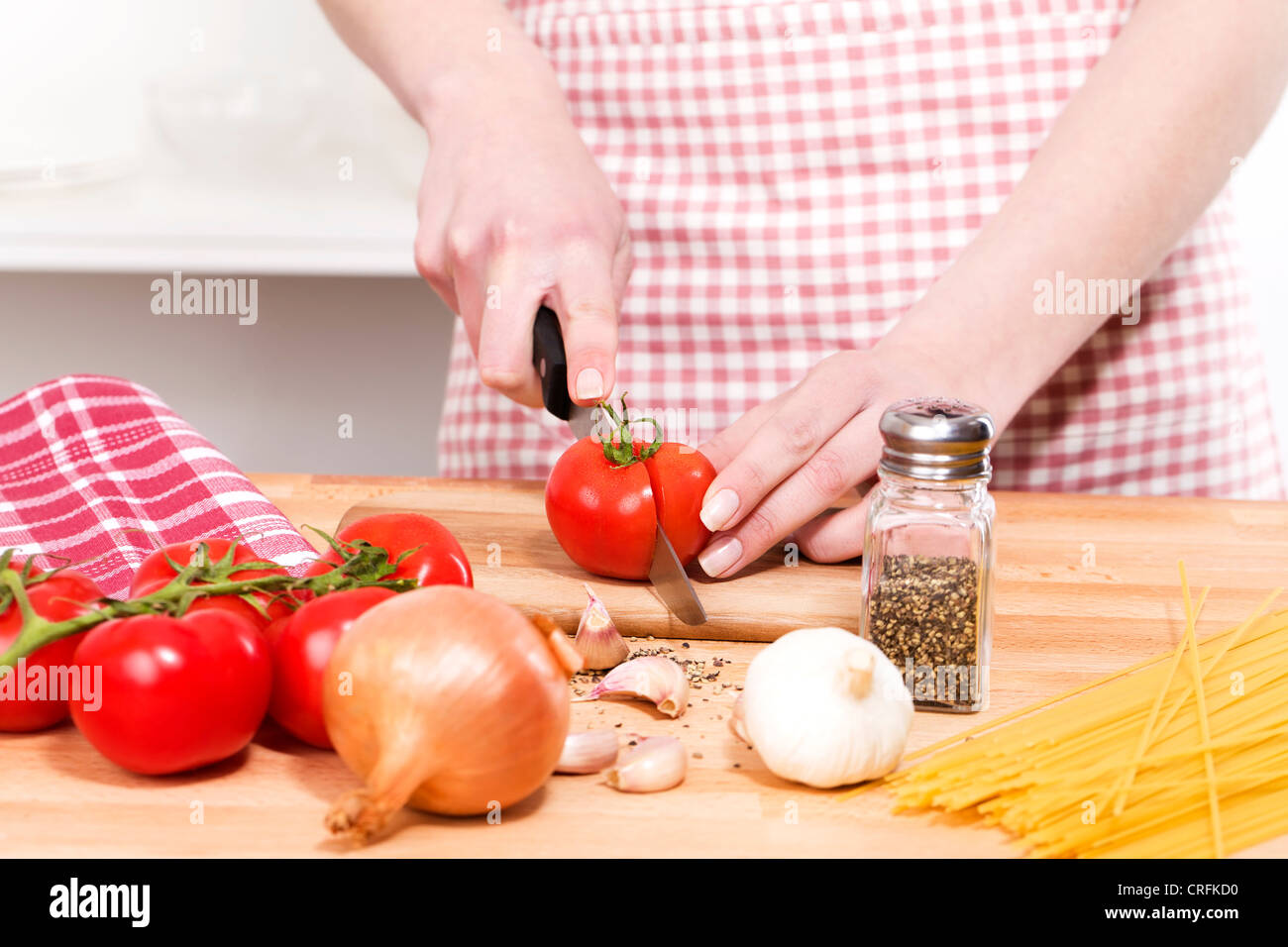 Primo piano delle mani il taglio di pomodori per spaghetti Foto Stock