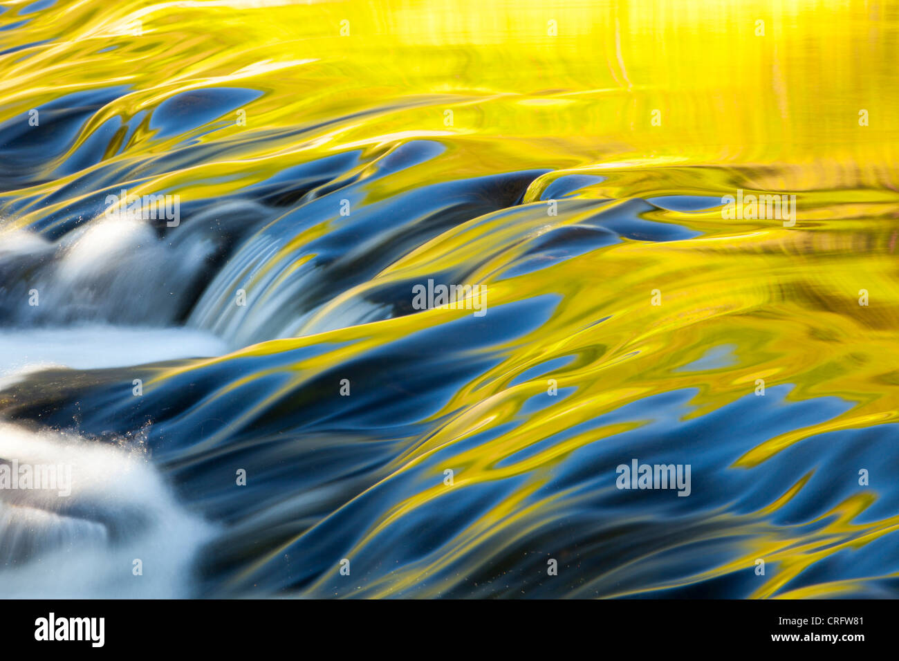 Riflessioni di calda luce della sera su acqua fluente lungoil weir in corrispondenza della bocca di uscita di Grasmere, Lake District, UK. Foto Stock