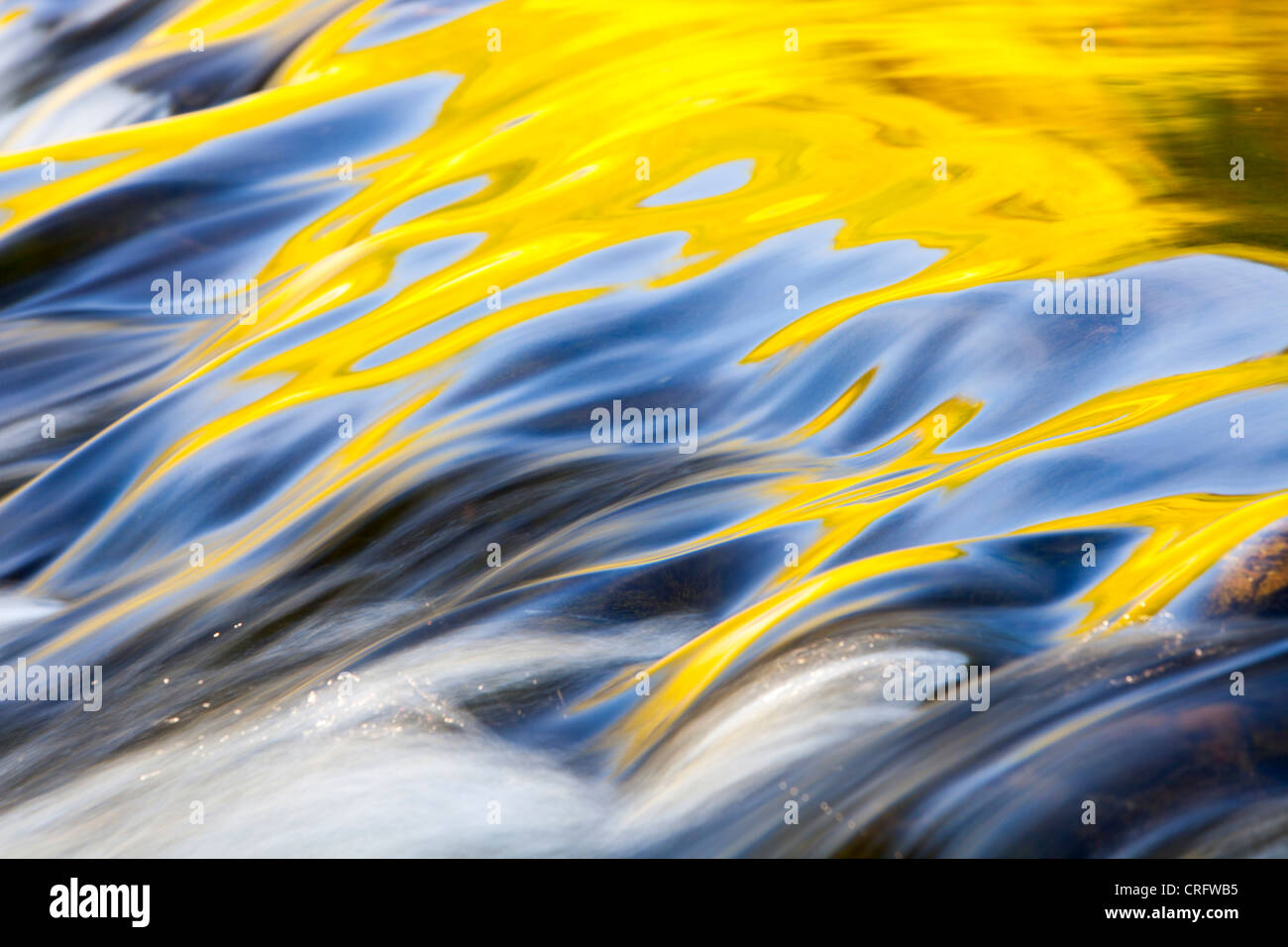 Riflessioni di calda luce della sera su acqua fluente lungoil weir in corrispondenza della bocca di uscita di Grasmere, Lake District, UK. Foto Stock