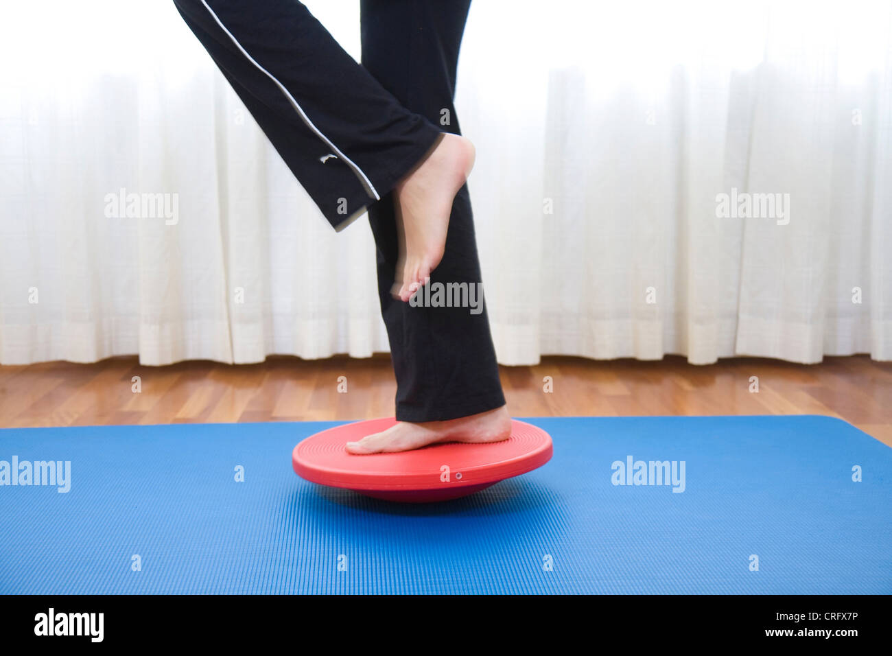 Giovane donna in equilibrio su un disco di bilanciamento Foto Stock