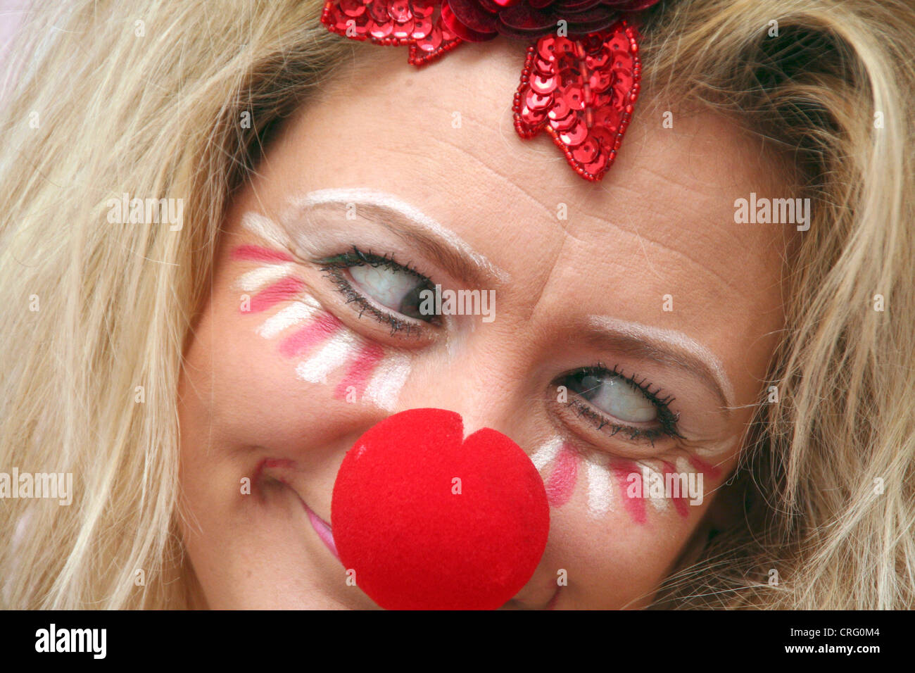 Strizzare gli occhi rouged donna bionda con naso rosso Foto Stock