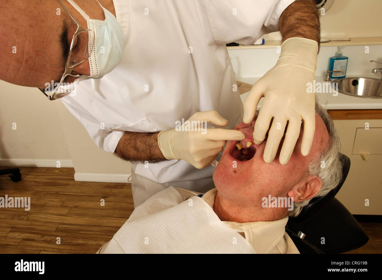 Un dentista esamina i tessuti molli della bocca di un paziente prima di iniziare il pieno trattamento dentale. Foto Stock