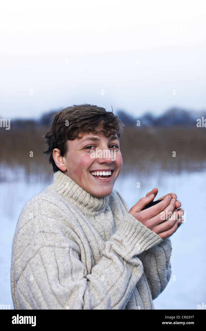 Uomo sorridente di bere il caffè nella neve Foto Stock