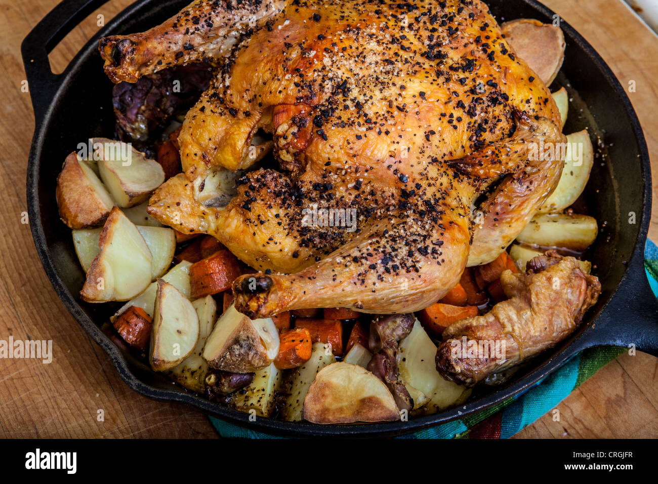 Un pollo arrosto con patate e carote in una ghisa padella Foto stock - Alamy