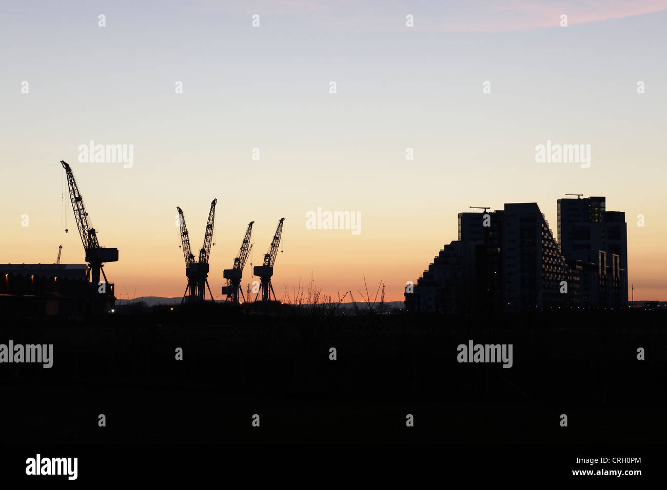 Tramonto sulle gru da cantiere BAE Systems a Govan e Glasgow Harbour Apartments, Glasgow, Scozia, Regno Unito Foto Stock