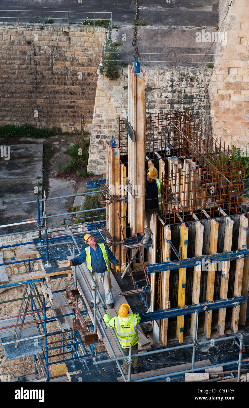 Operai edili che inseriscono nuovi pali in calcestruzzo per rinforzare le vecchie mura della città di la Valletta, Malta Foto Stock