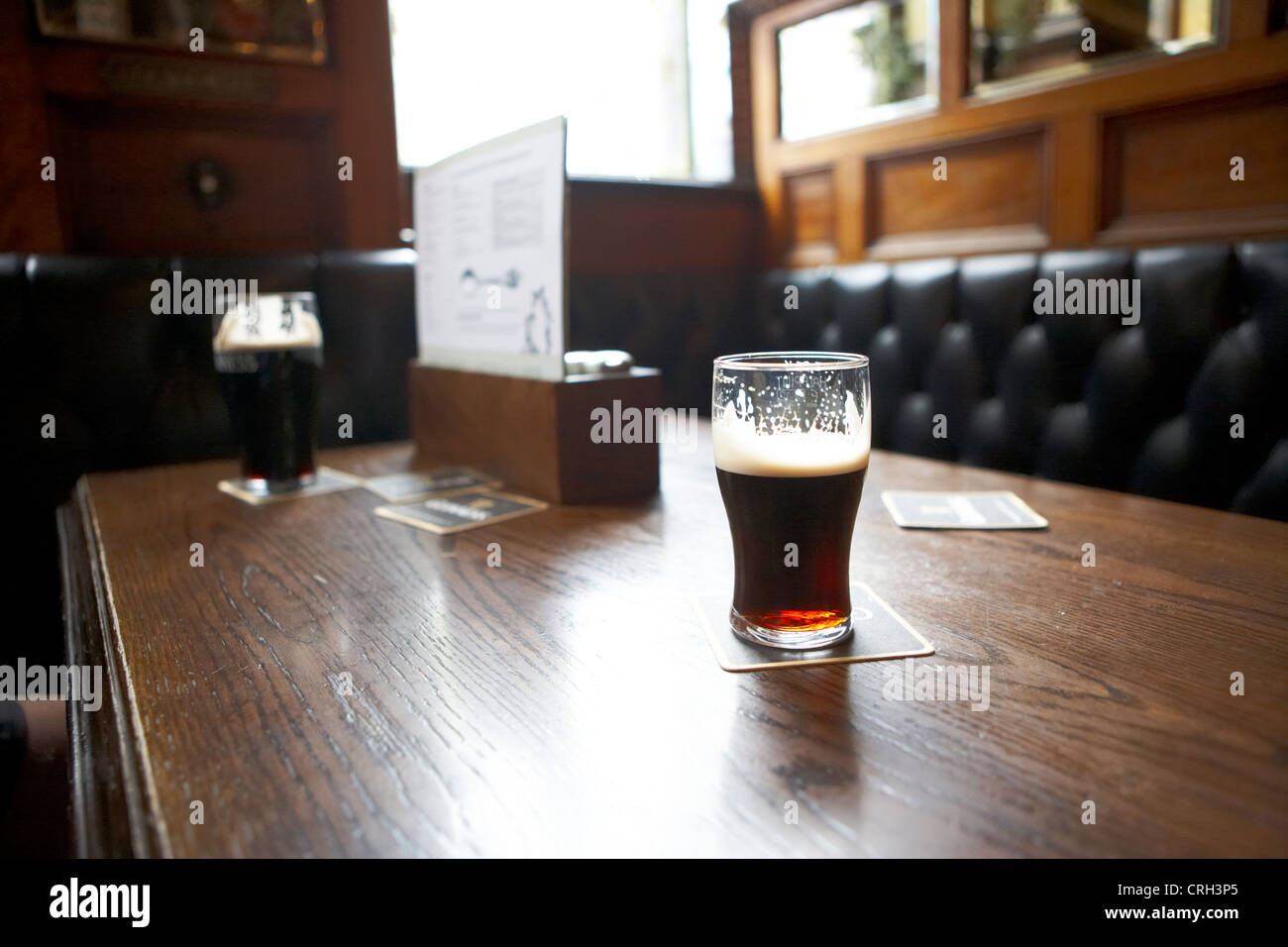 pinta di stout sul tavolo di una cabina all'interno del bar pub crown liquor berlina a belfast, irlanda del nord, regno unito Foto Stock