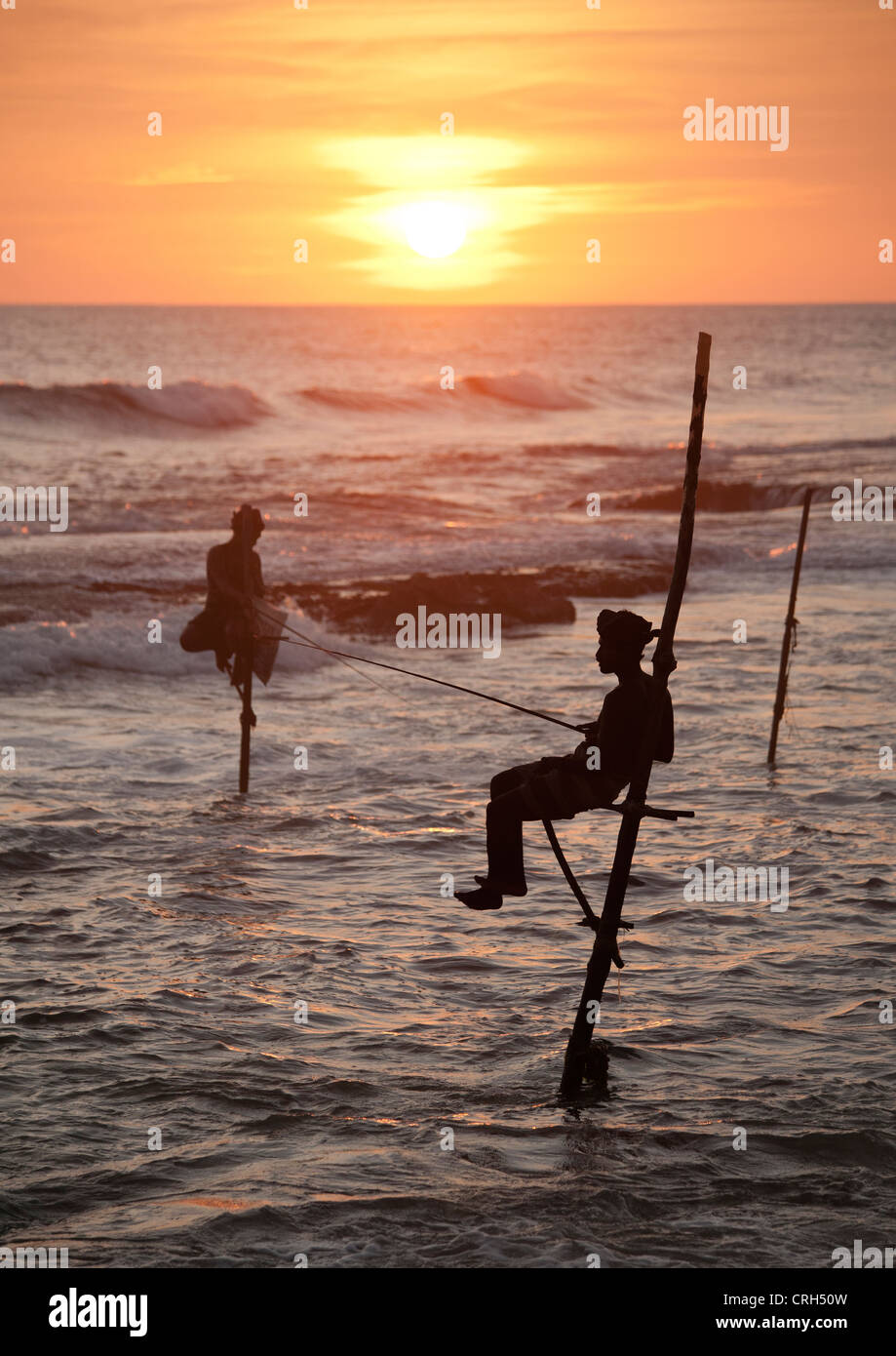 Stilt pescatori al tramonto di sera Weligama sull'Oceano Indiano Sri Lanka Foto Stock