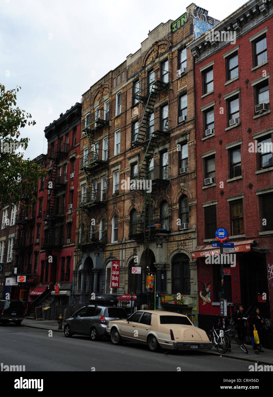 Vista obliqua di mattoni rossi blocchi tenement, 'Fisico Graffiti edificio", automobili parcheggiate, St Mark, East Village, New York Foto Stock