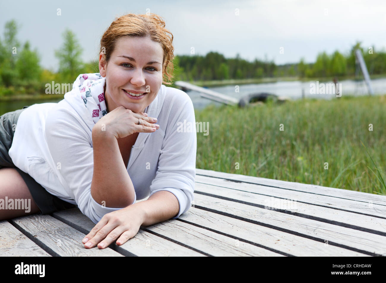 Sorridenti donna posa su tavole di legno sul bordo del fiume. Copyspace Foto Stock