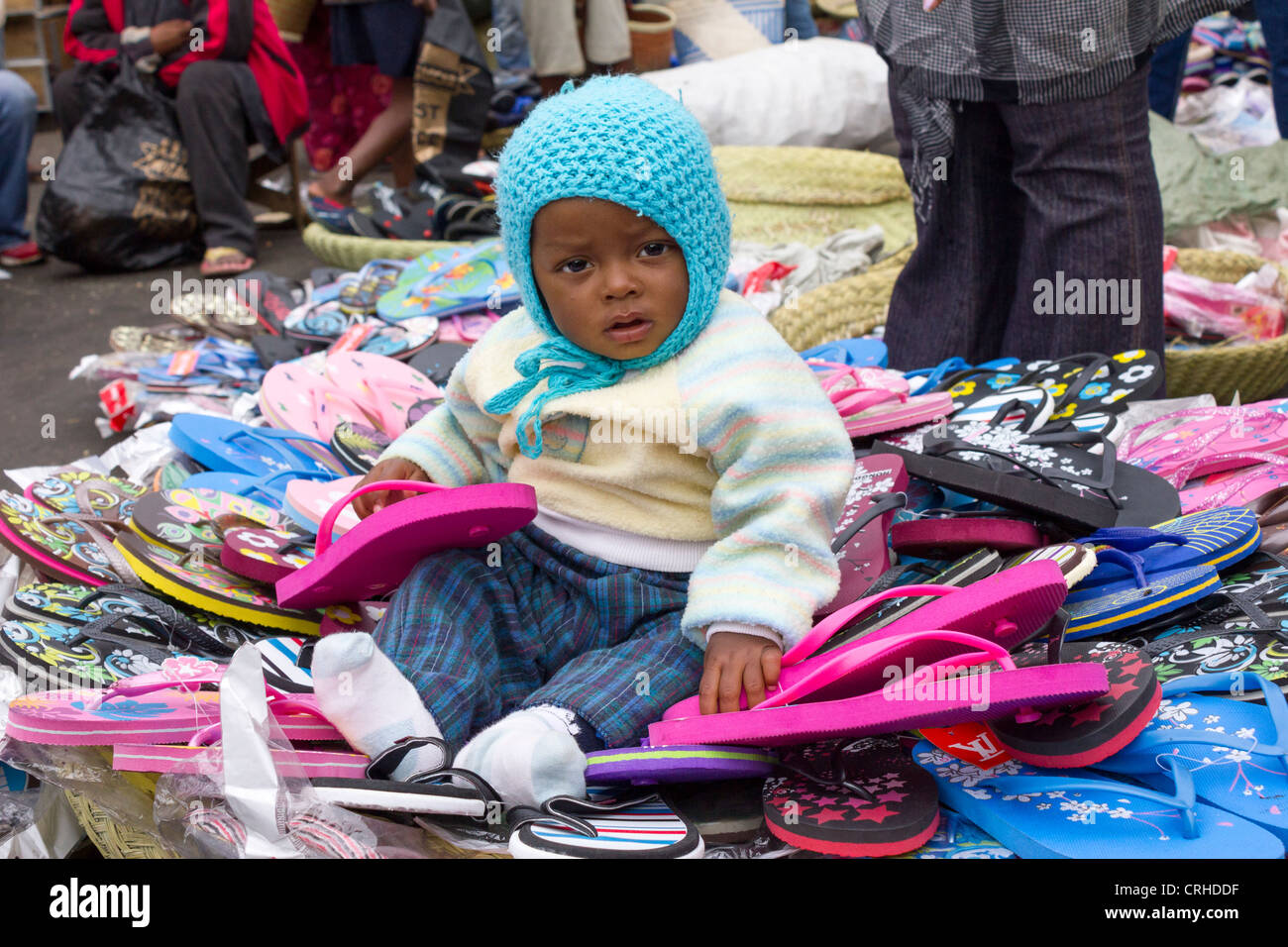 Il bambino gioca con sandali di plastica in stallo, Analakely market, Antananarivo, Madagascar Foto Stock