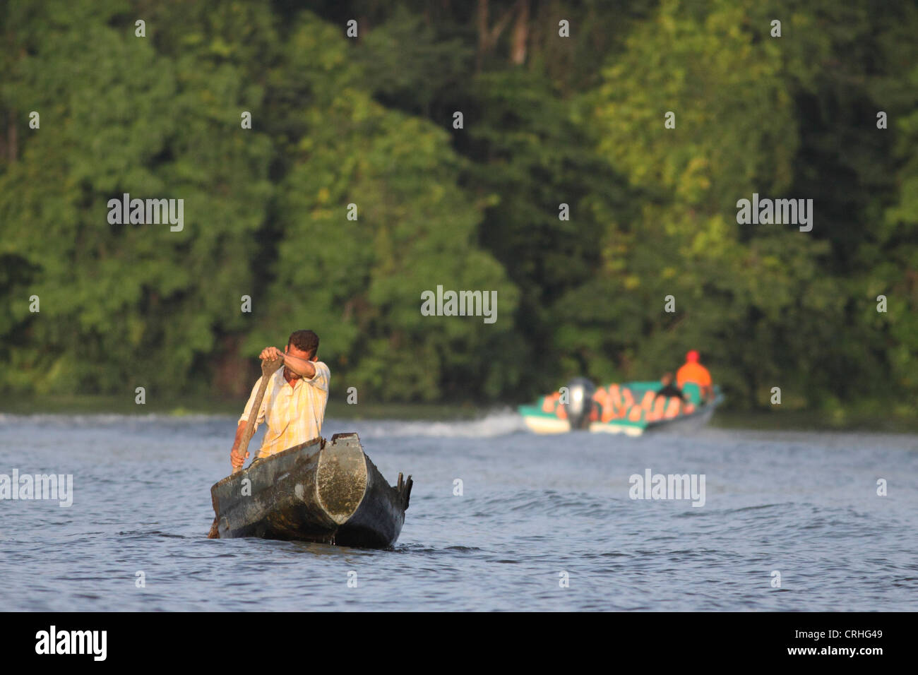 Imbarcazione turistica passa abitante in canoa sulla foresta pluviale naturale canal. Parco Nazionale di Tortuguero. Costa Rica. Ottobre 2011. Foto Stock
