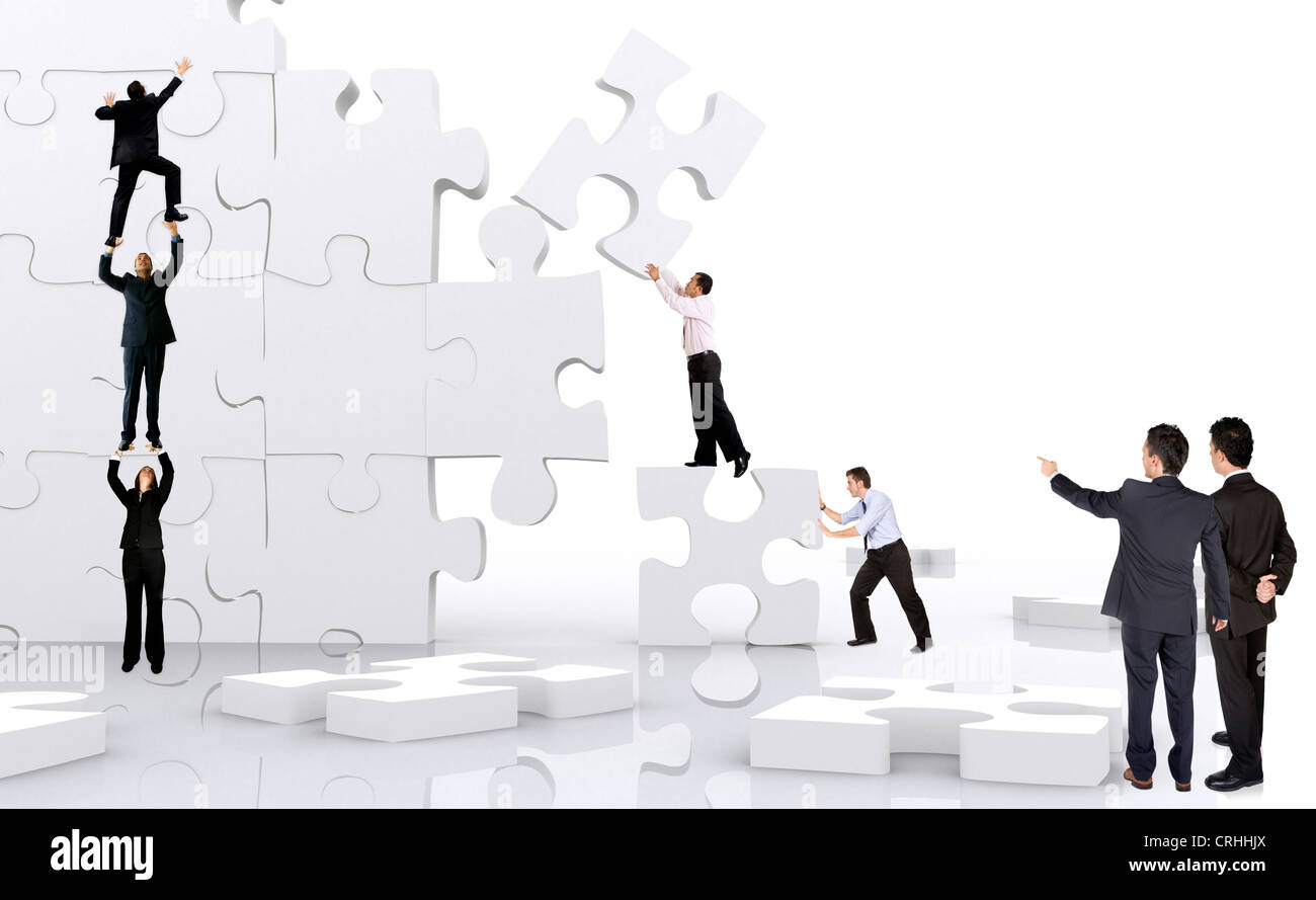 I giovani uomini di affari che la costruzione di un muro di gigante i pezzi del puzzle Foto Stock