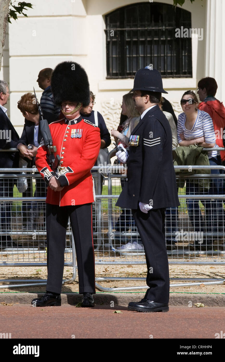 Guardsman in piedi a parlare con un poliziotto metropolitano sul Mall London Inghilterra England Foto Stock