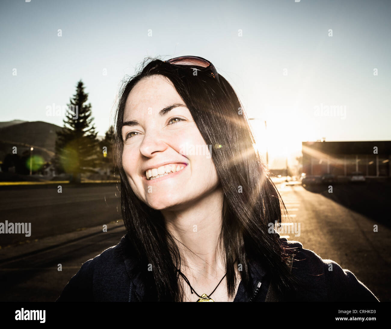 Donna sorridente e sun flare all'aperto Foto Stock