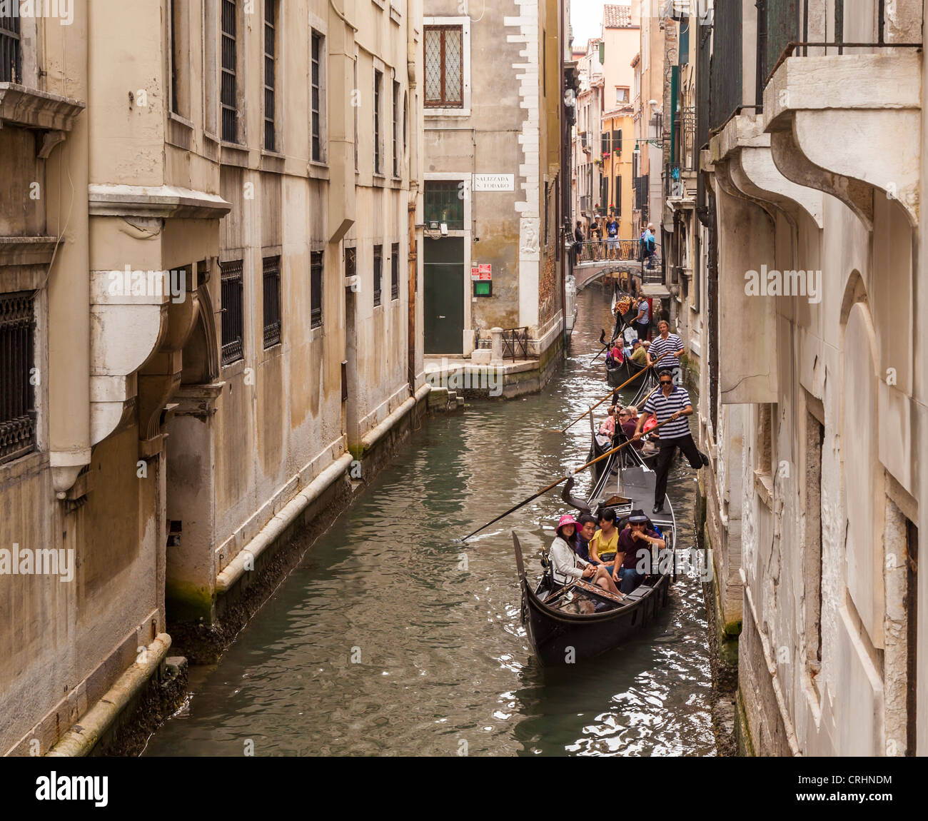 Tre gondole con passeggeri che viaggiano attraverso uno stretto canale.in una stretta Foto Stock
