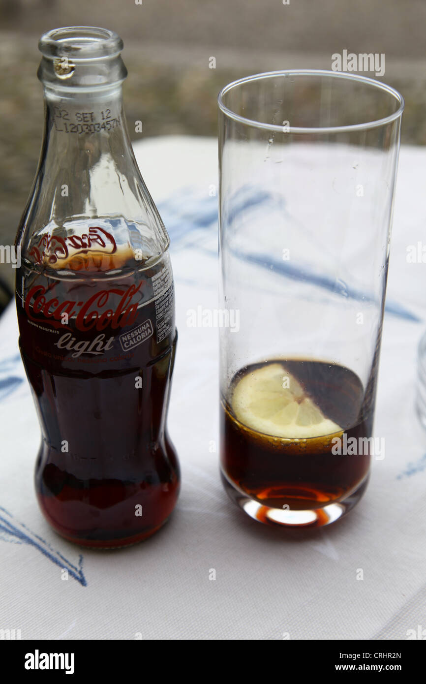 Un italiano di forma classica di Bottiglia di Coca Cola Light e un bicchiere con una fettina di limone in esso su un tavolo Foto Stock